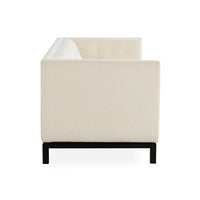 A modern low-profile armchair with textured cream upholstery and a black metal frame, shown from a rear three-quarter angle on a white background.