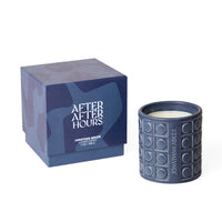 Jonathan Adler After After Hours scented candle in a textured navy blue ceramic jar next to its matching branded packaging box on a white background.