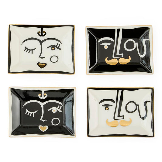 Four square ceramic dishes with artistic face designs on a white background