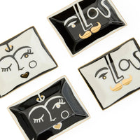 Four decorative trinket dishes with face designs on a white background