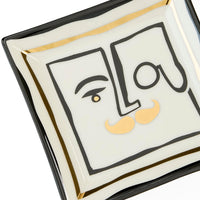 Decorative plate with artistic face design and 'Lou' text on a white background