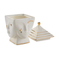 Decorative white container with gold accents resembling a face, on a white background