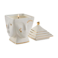 Decorative candle in a face-shaped holder with a matching pyramid-shaped lid on a white background