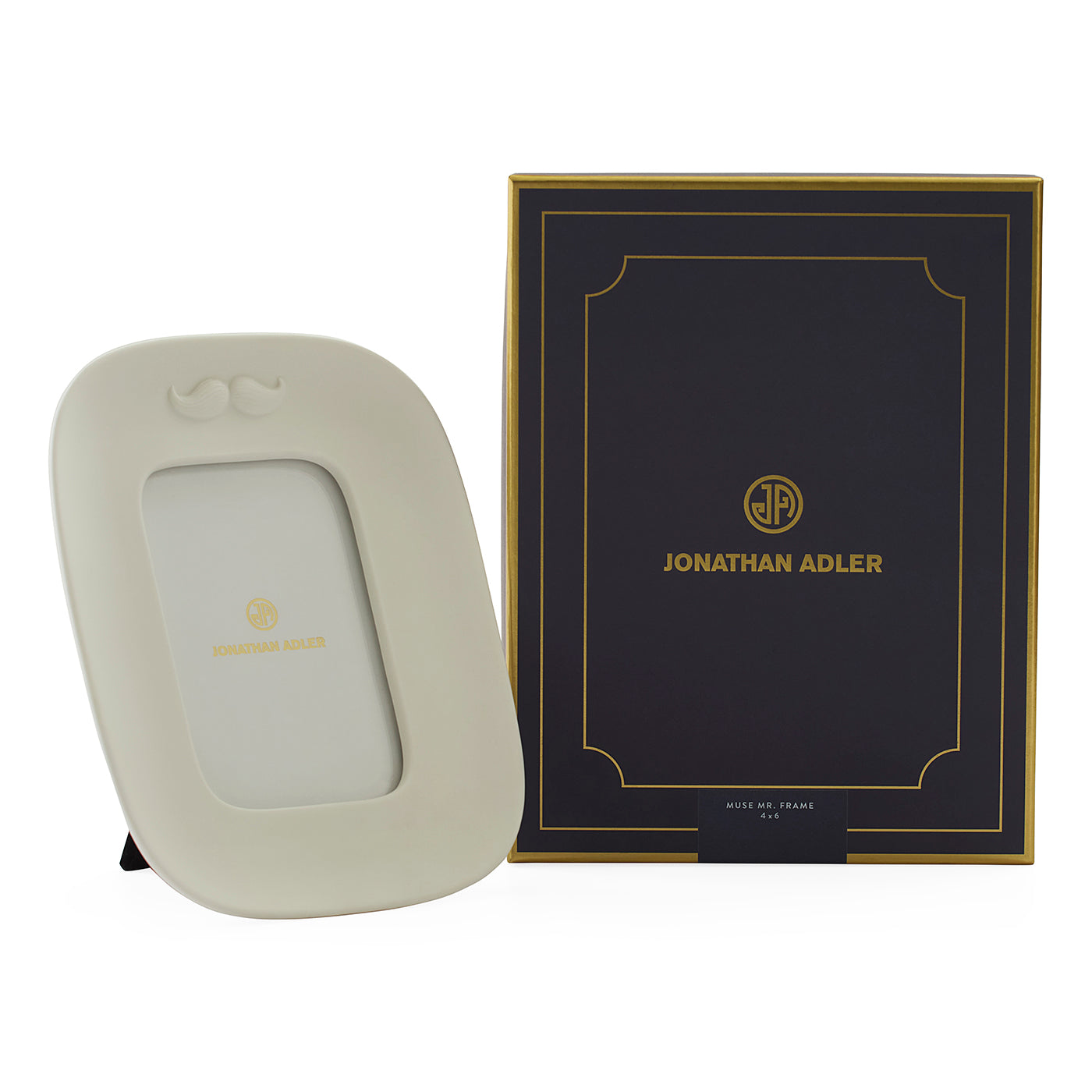 A cream-colored Joseph Louis Mount picture frame with a small gold Jonathan Adler logo, shown next to its dark navy and gold presentation box on a white background.
