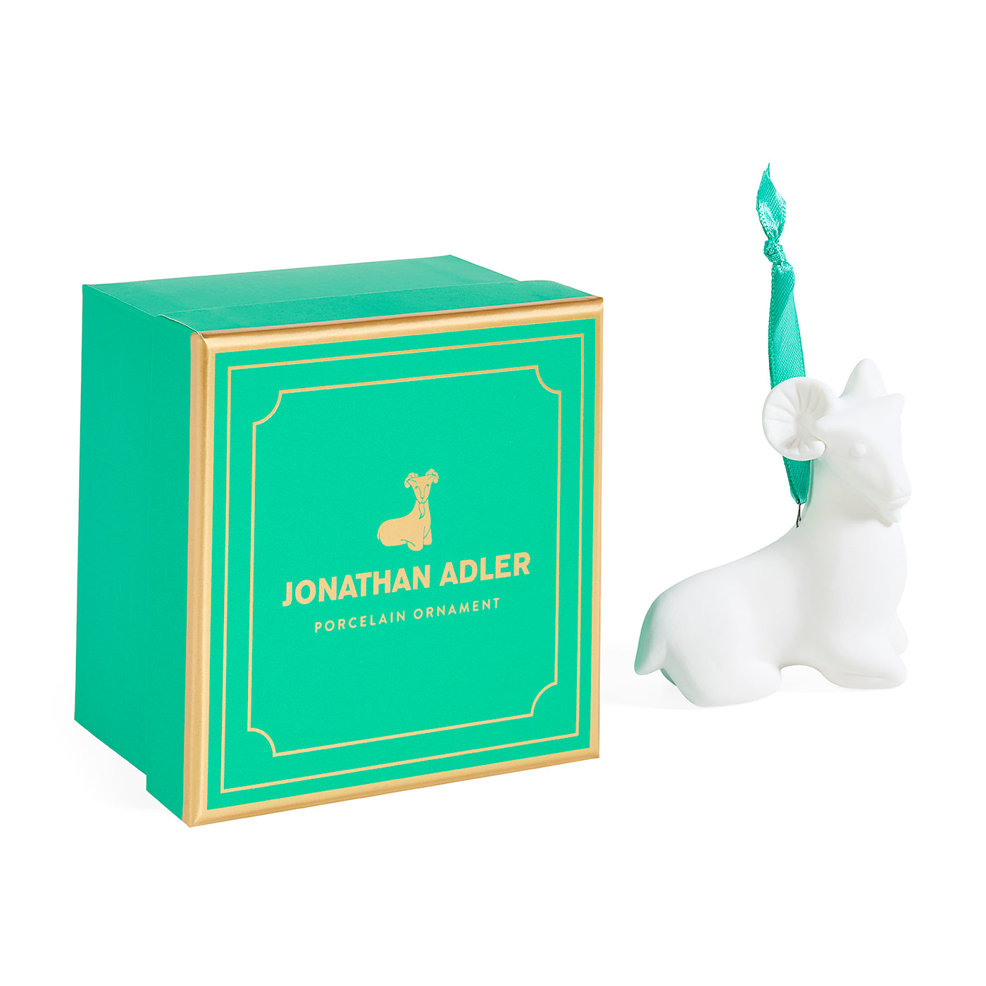 A white ceramic ram ornament by Jonathan Adler next to its signature green and gold gift box on a clean white background.