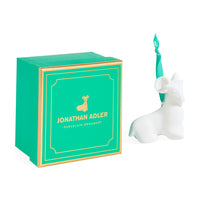 A white ceramic ram ornament by Jonathan Adler next to its signature green and gold gift box on a clean white background.