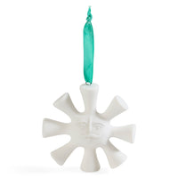 A white ceramic ornament shaped like a sun with a face and rays, hanging from a shiny teal ribbon on a white background.
