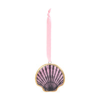 A scallop shell-shaped ornament with a pink and black fan pattern, framed in gold, hanging from a pink ribbon on a white background.