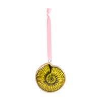 A circular ornament featuring a yellow and black ammonite fossil design, suspended by a light pink ribbon on a white background.