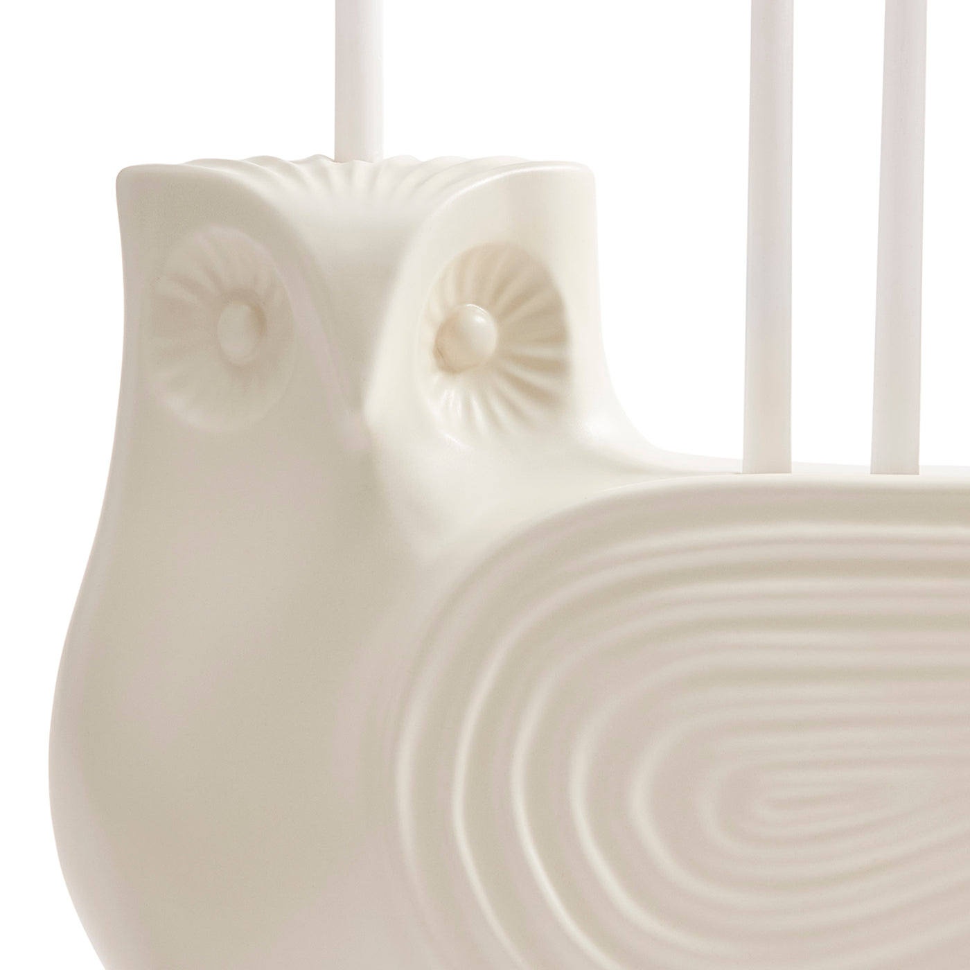 Close-up of a glossy white ceramic owl-shaped candle holder with carved owl eyes and a ribbed body, holding white candles against a bright white background.
