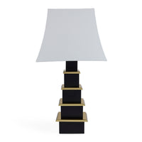 Table lamp with a white shade and black base with gold accents on a white background