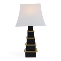 Table lamp with a white shade and black and gold base on a white background