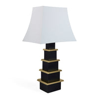 Table lamp with a black and gold base and white shade on a white background