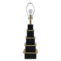 Black and gold lamp with a white light bulb on a white background