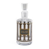 A clear glass decanter with a matching stopper, featuring a decorative label with gold and black classical columns and the text 'PICK YOUR POISON'.