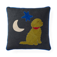 A square dark gray throw pillow with a blue piped edge, featuring an embroidered design of a golden dog wearing a red collar, a blue star, and a cream crescent moon.