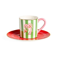 Ceramic cup with pink handle and green striped design on a red saucer