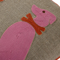 Close-up of a textured woven cushion featuring a stylized pink dog design with a rust-brown collar on a taupe-beige fabric background.