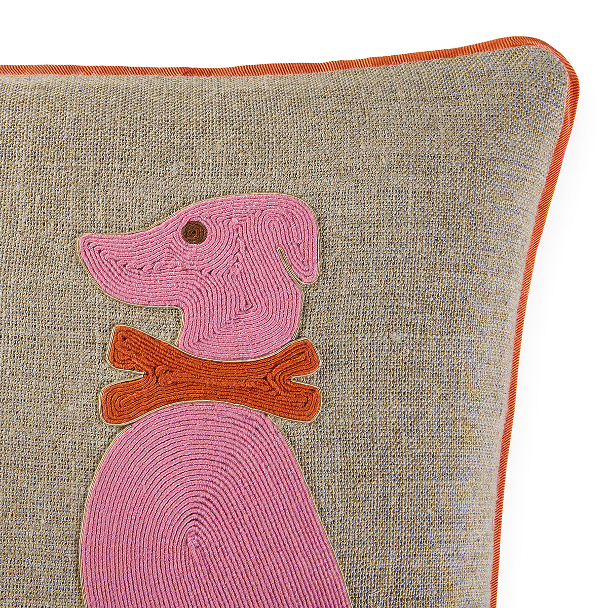 Close-up of a textured beige throw pillow with a pink embroidered dog and an orange collar, finished with an orange piped edge.