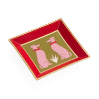 A square ceramic dish with a glossy red interior, a gold rim, and a central olive-green panel featuring two pink dogs wearing red bows on a white background.
