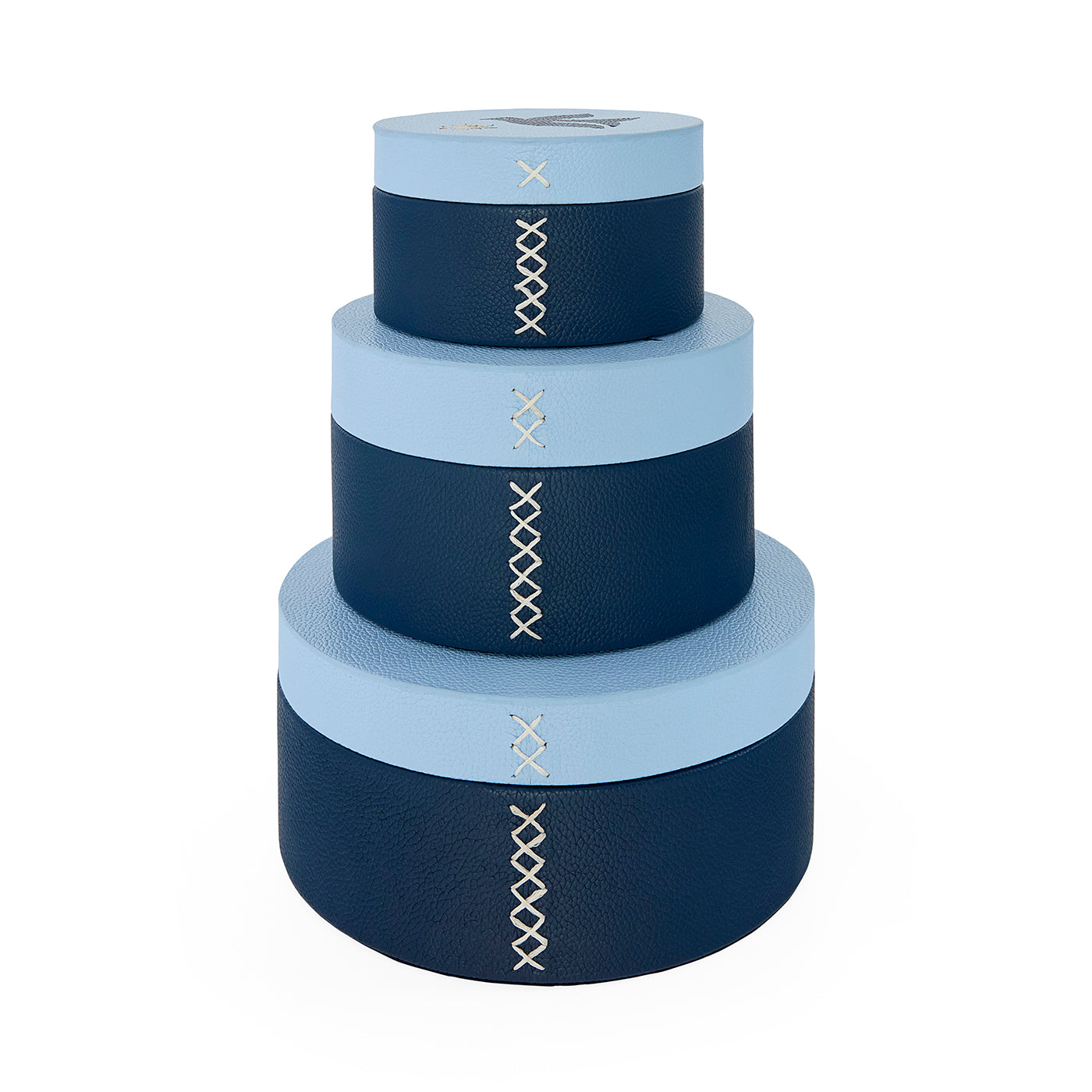 Set of four navy and light blue cylindrical boxes with decorative stitching on a white background