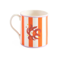 Mug with orange and white striped pattern and a brown fish design on a white background
