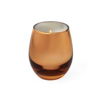 An amber glass candle holder with a lit candle inside, set against a plain white background.