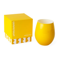 A bright yellow stemless wine glass next to its matching yellow packaging box, which features the text 'GRAPEFRUIT' and 'JONATHAN ADLER' on a clean white background.