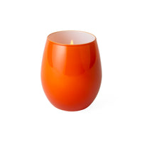 A glossy orange glass candle holder with a lit flame, shown on a solid white background.