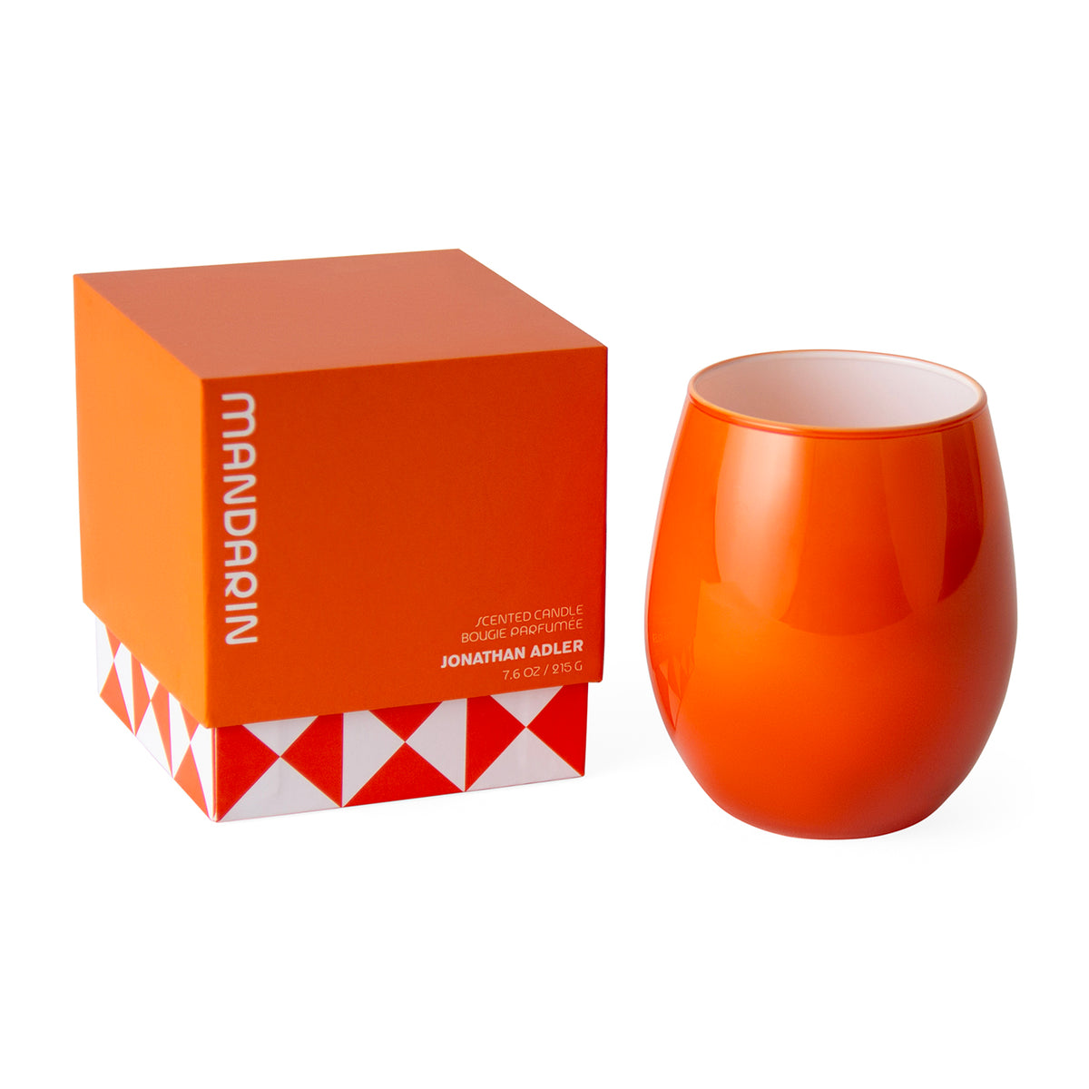 Jonathan Adler Mandarin scented candle in an orange glass vessel next to its orange and white patterned box, on a white background.
