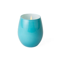 A glossy teal blue ceramic candle holder with a lit candle inside, set against a plain white background.