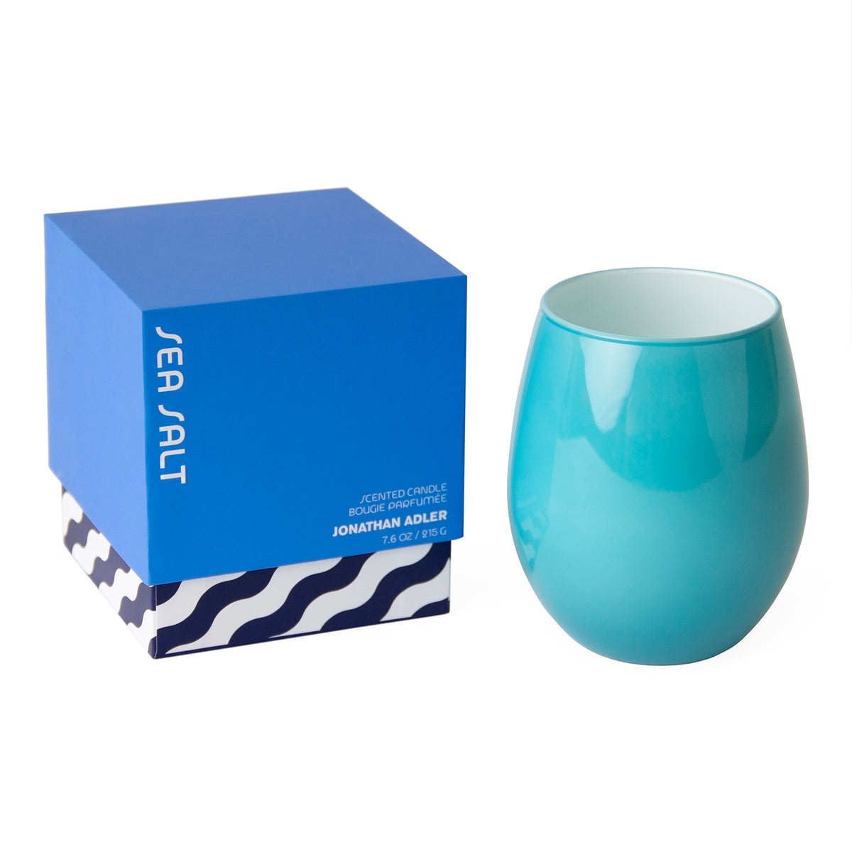 A turquoise ceramic candle holder with a rounded stemless shape, shown next to its blue Jonathan Adler 'Sea Salt' branded gift box on a white background.