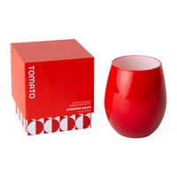 A red scented candle and its packaging box by Jonathan Adler, shown on a clean white background. The box is bright red with white text reading 'TOMATO' and the brand name, and the candle itself is a matching glossy red stemless glass vessel.