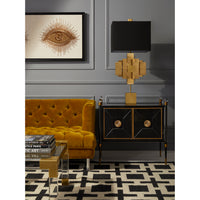 Modern living room with yellow sofa, black and gold side table, and abstract art on gray wall.