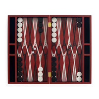 An open backgammon set with a deep red and black checkered board, white and black round tokens, dice, and gold-tone hinges, photographed against a plain white background.