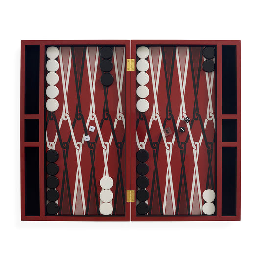 An open backgammon set with a deep red and black checkered board, white and black round tokens, dice, and gold-tone hinges, photographed against a plain white background.