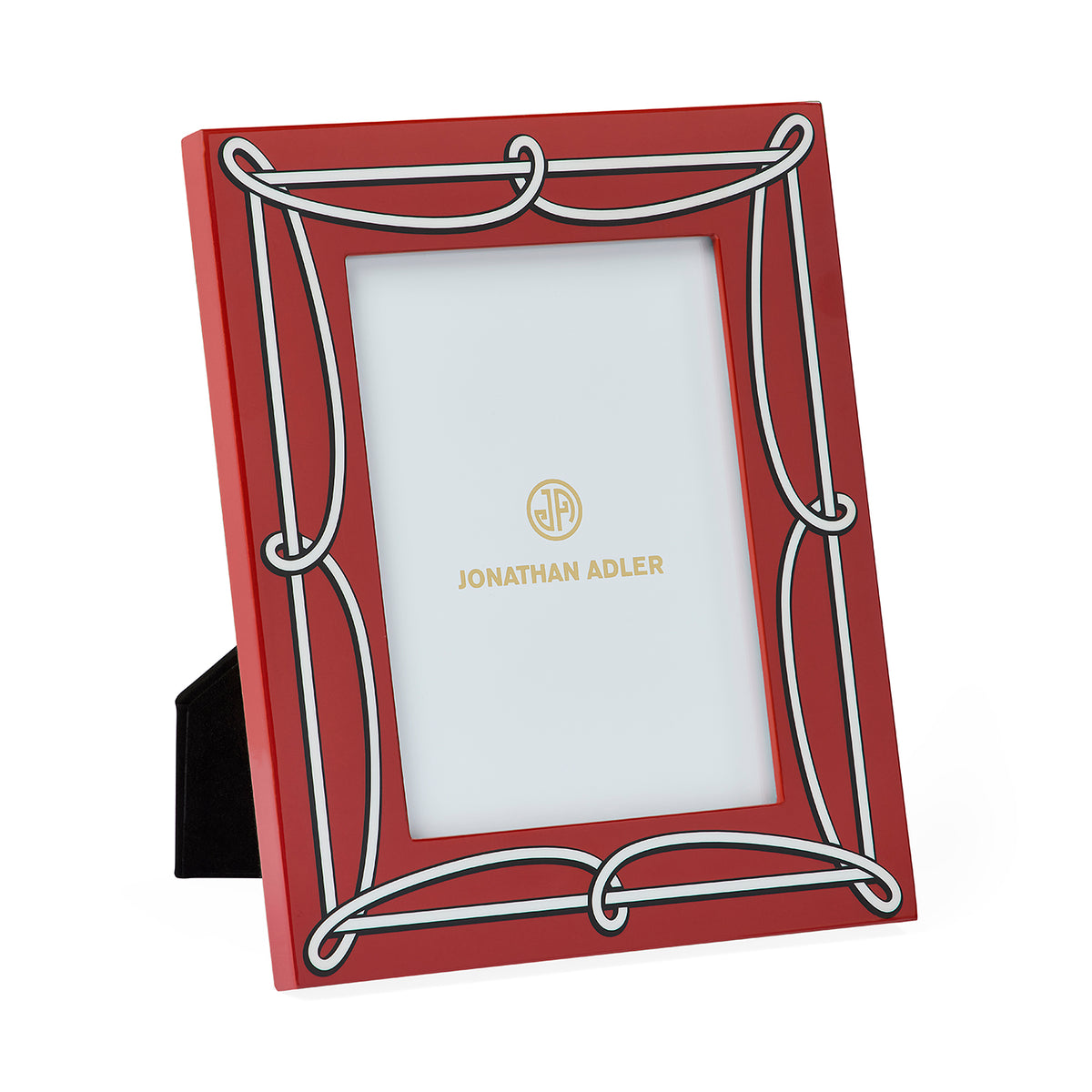 A red picture frame with a white decorative border and a black easel stand, featuring the gold Jonathan Adler logo printed on the insert.