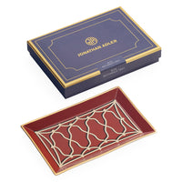 Jonathan Adler Muta Rectangle Tray in deep red with gold and cream geometric detailing, shown alongside its navy blue and gold presentation box.