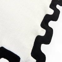 Close-up of a white textured fabric with a bold black wavy scalloped border trim.