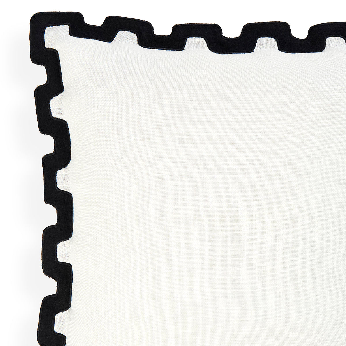 A close-up of a white textile product, likely a napkin or table linen, featuring a thick black scalloped or wavy border along one corner.