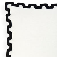 A close-up of a white textile product, likely a napkin or table linen, featuring a thick black scalloped or wavy border along one corner.