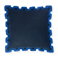 A square throw pillow in dark navy blue fabric with a contrasting bright blue jigsaw puzzle-edge border, shown on a plain white background.