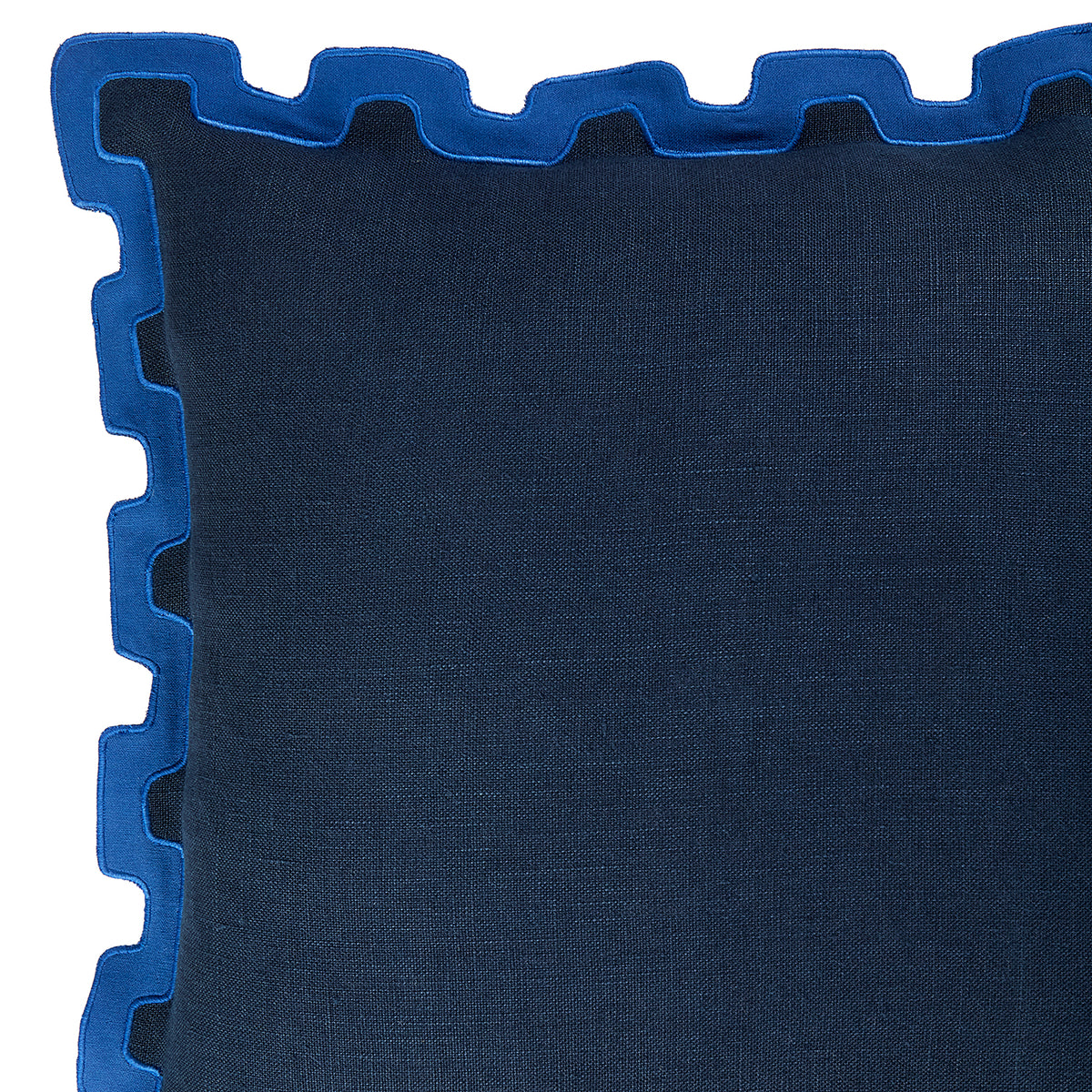 Close-up of a dark blue textured throw pillow with a contrasting bright blue scalloped edge trim, shown against a white background.