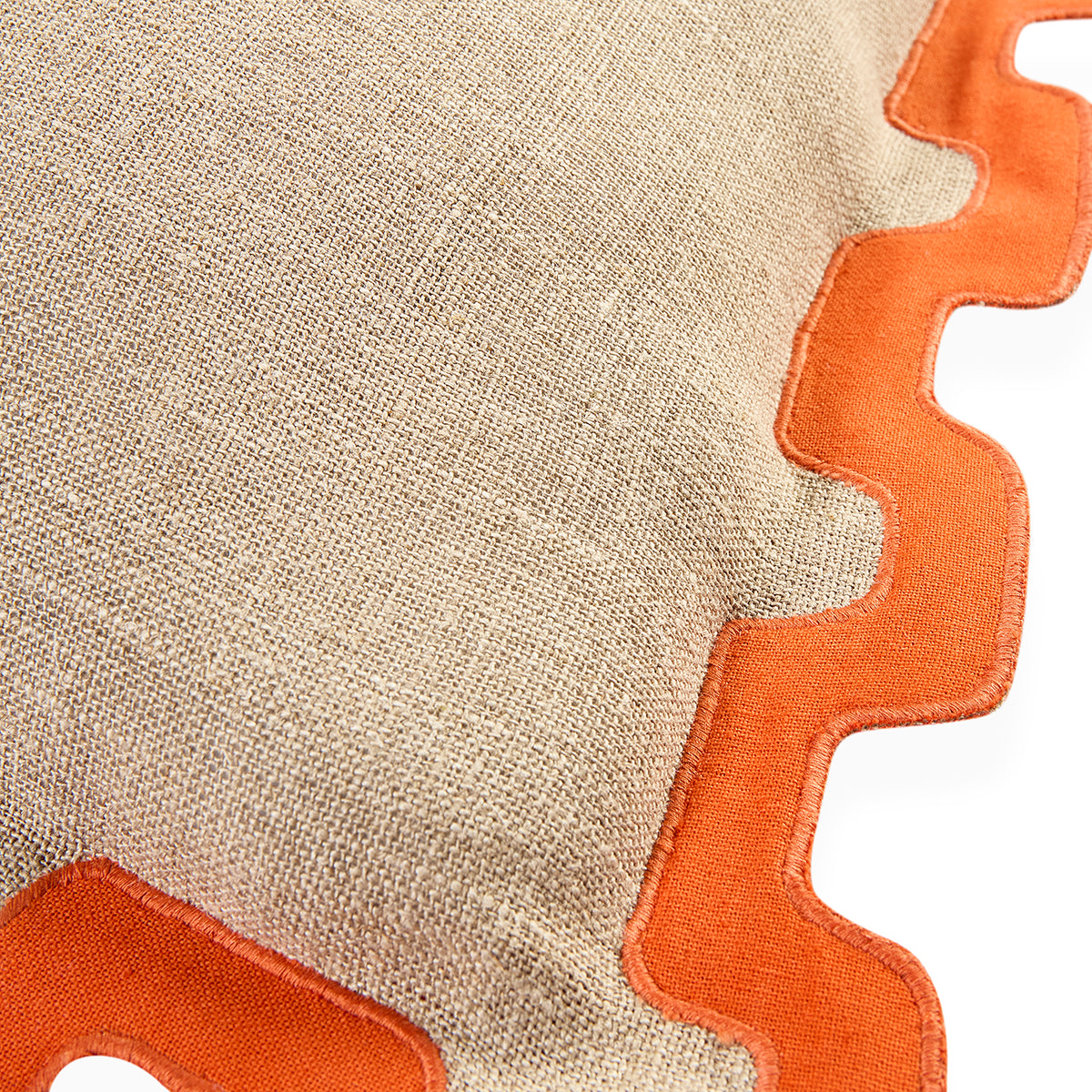 Close-up of a woven beige textile with a bright orange scalloped border on a white background.