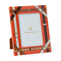 Jonathan Adler picture frame with a bright orange background and an all-over brown and cream leather-buckle print, shown standing on a small matching base against a white background.