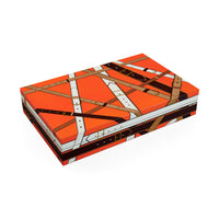 A rectangular product box with a bold orange, brown, white, and black leather-buckle-inspired geometric pattern, shown at an angle on a plain white background.