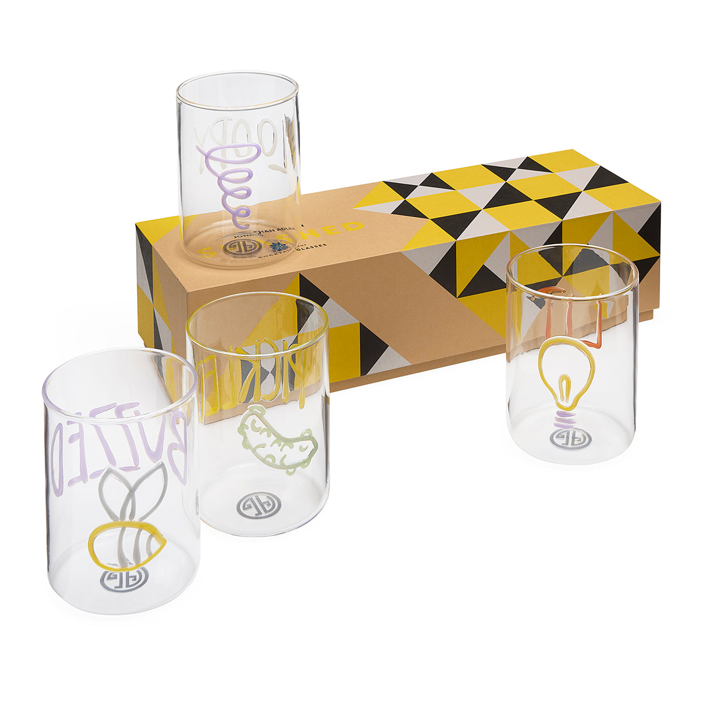 Three clear glass tumblers with colorful printed graphics are displayed in front of a patterned brown, yellow, and black gift box on a white background.