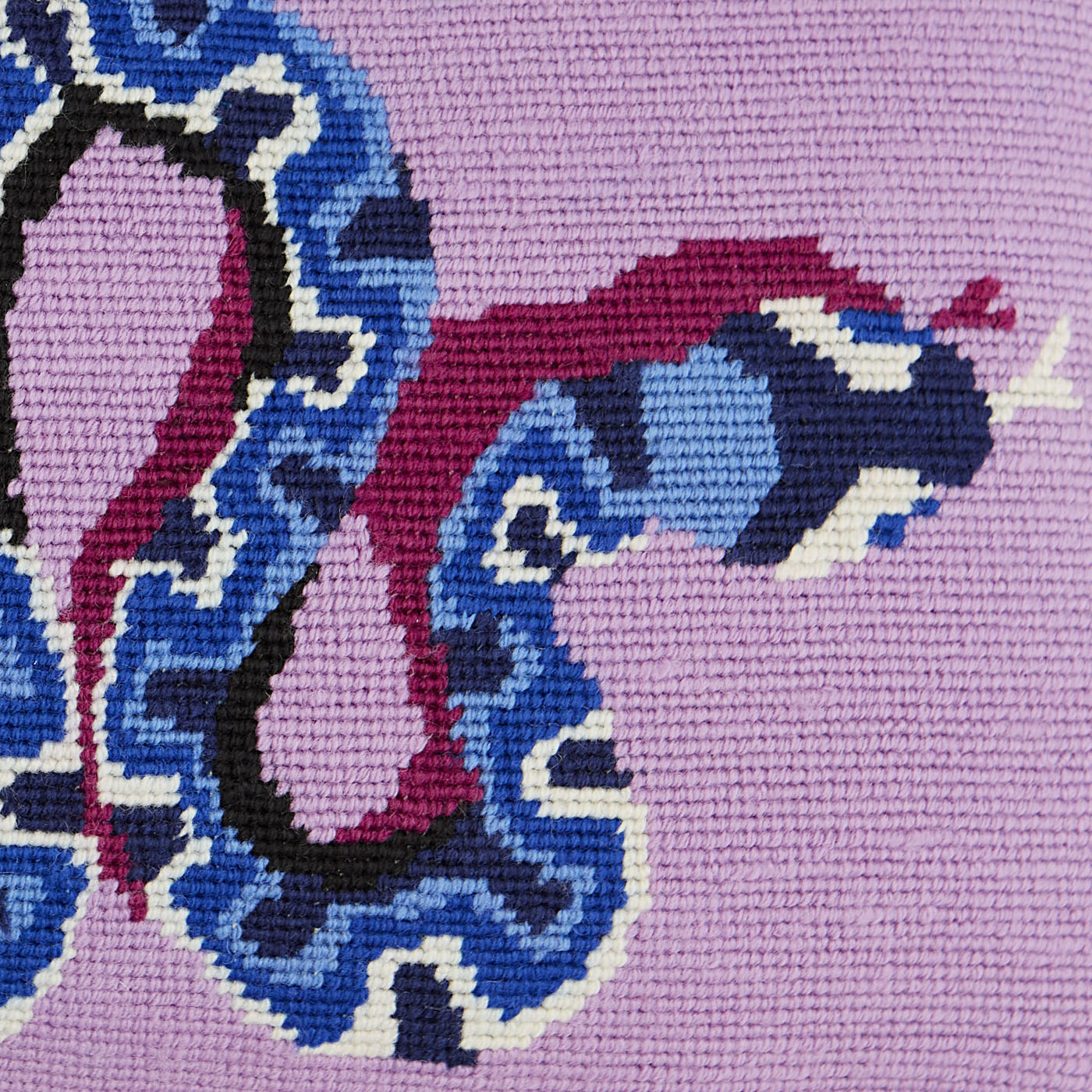 Close-up of a cross-stitched design on fabric with blue, pink, and black colors.