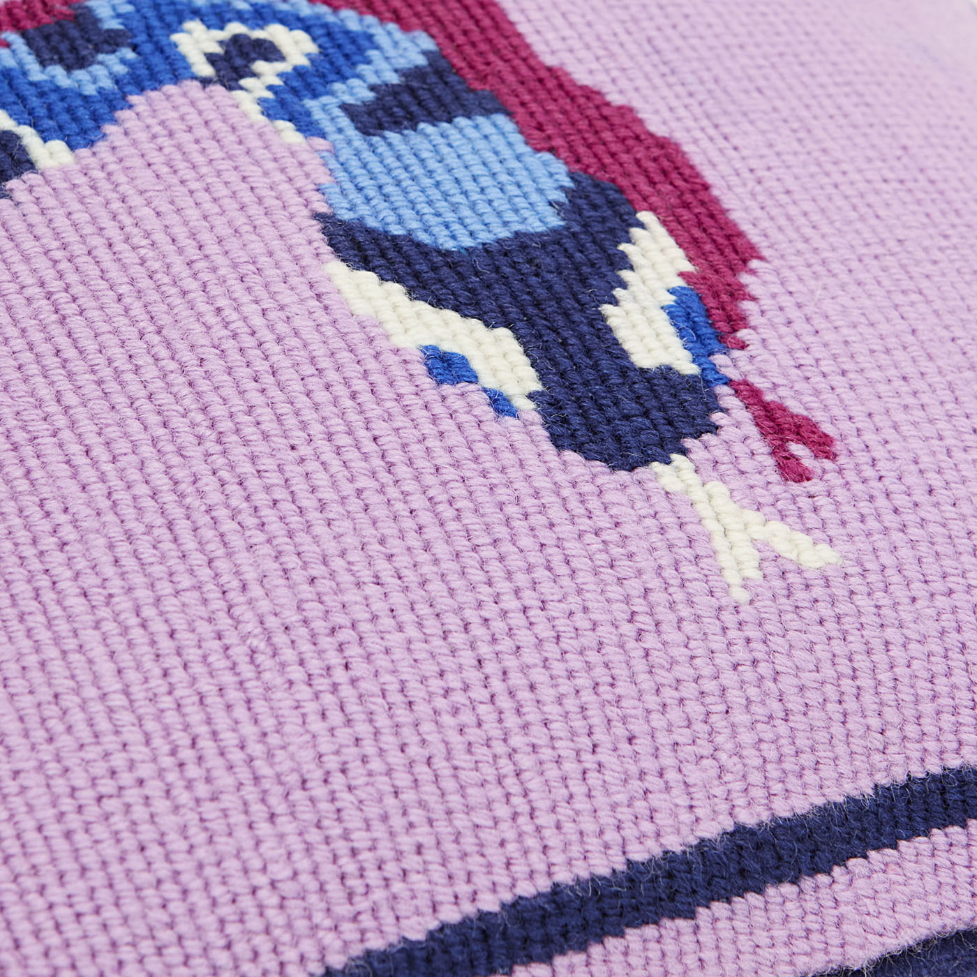 Close-up of a cross-stitched design on fabric with a pink background