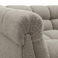 Close-up of a textured gray sofa with tufted backrests.